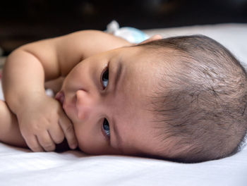 Close-up portrait of baby lying on bed