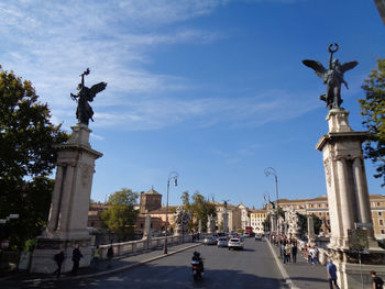 Statue in city against sky