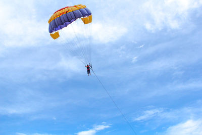 Low angle view of person paragliding against sky