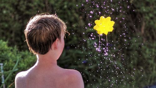 Rear view of shirtless boy by toy in mid-air