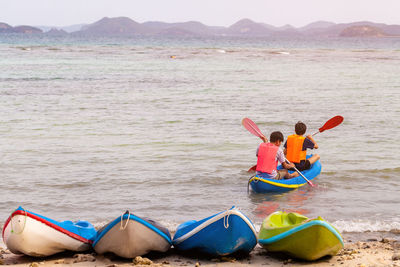 Rear view of father and son rowing on sea