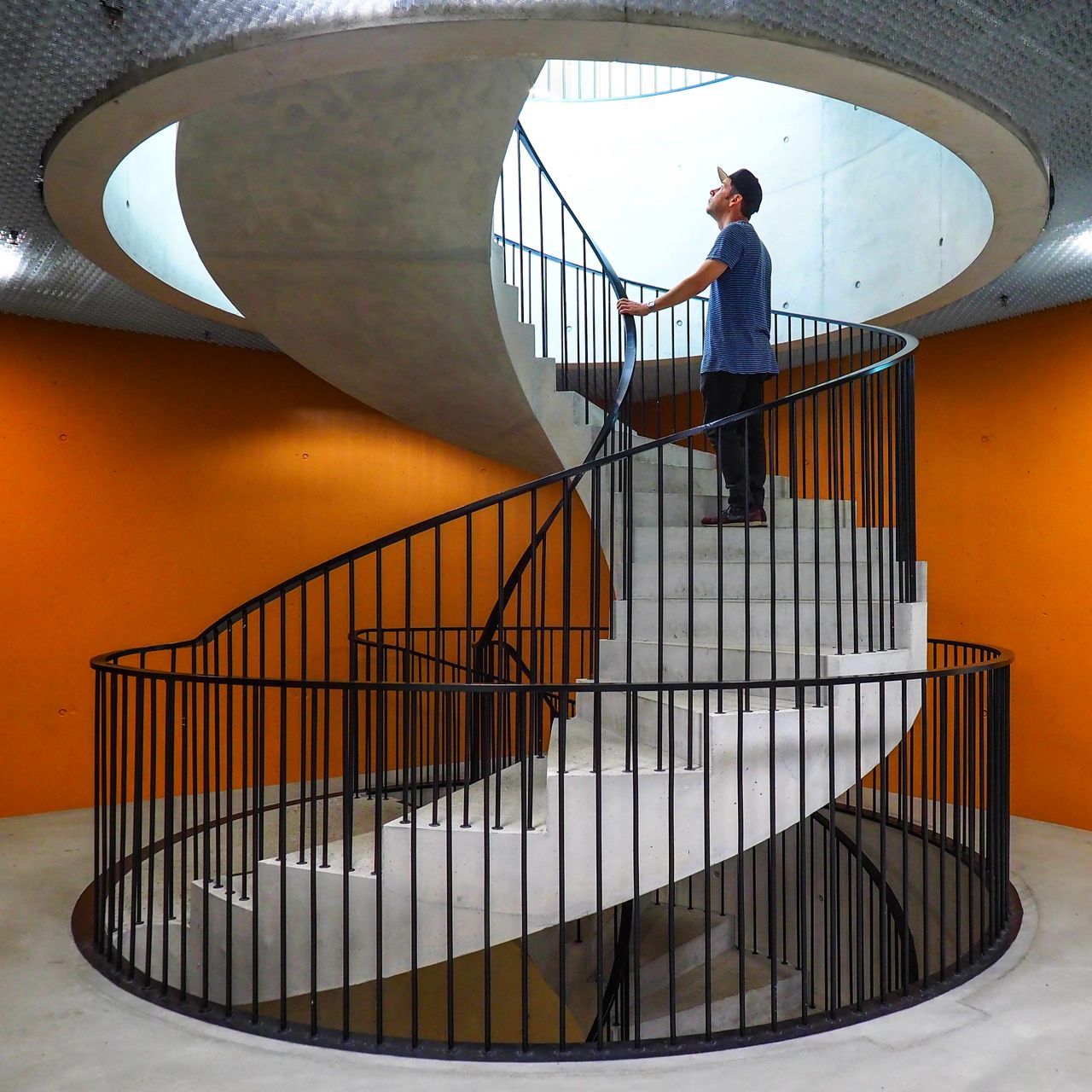 MAN STANDING ON STAIRCASE IN CORRIDOR