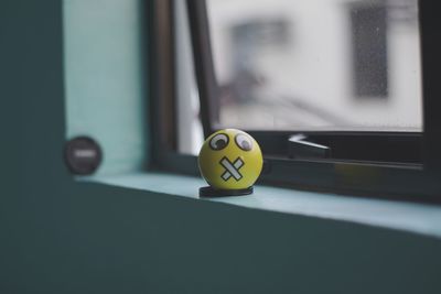 Close-up of anthropomorphic face on yellow ball against window