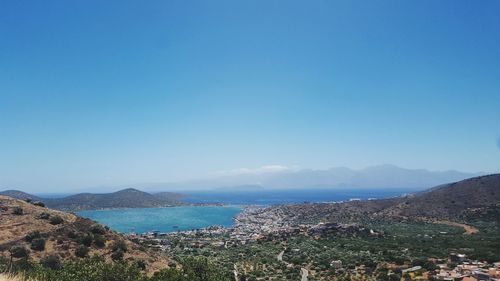 Scenic view of sea and mountains against clear blue sky