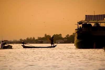 Silhouette people on sea against clear sky during sunset