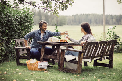 Couple serving water to woman at breakfast table in organic farm