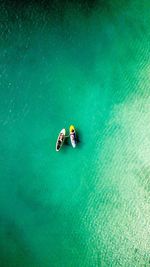 Aerial view of couple relaxing on paddleboards in sea