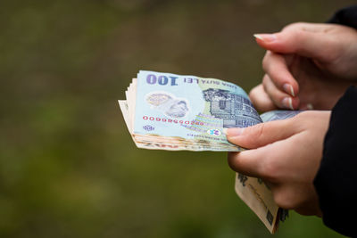 Cropped image of hand holding paper against blurred background