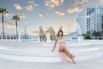 Portrait of young woman in swimming pool against sky