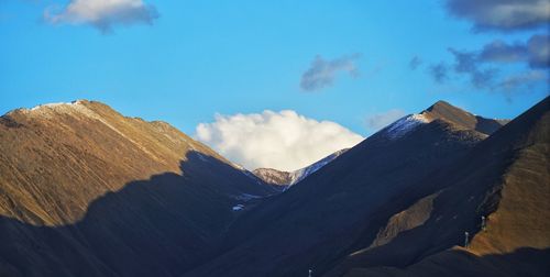 Low angle view of snowcapped mountains against blue sky