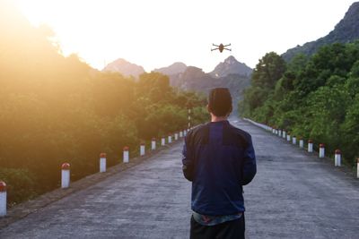 Rear view of man standing on road against sky