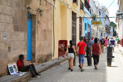 People walking on street amidst buildings in city