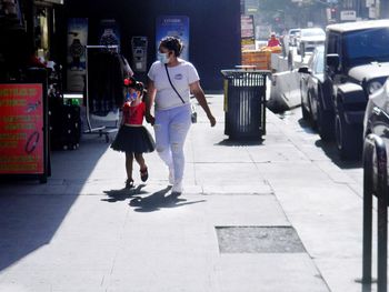 Rear view of women walking on sidewalk