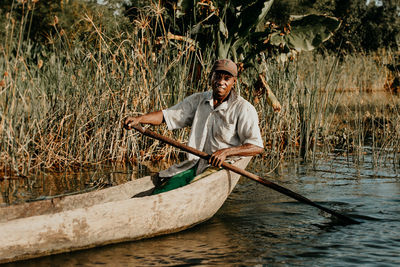 Full length portrait of a man holding boat in water