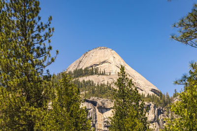 Low angle view of rocky mountain against clear blue sky