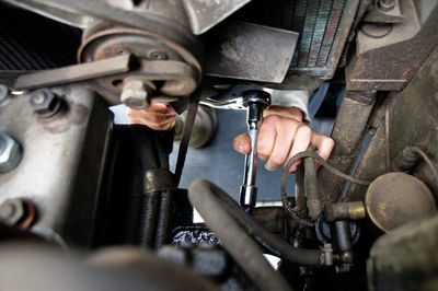 Cropped hand of mechanic repairing motor vehicle at auto repair shop