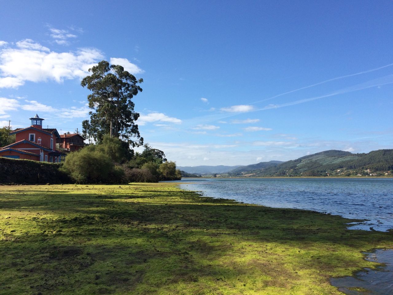 sky, water, blue, tree, building exterior, tranquil scene, built structure, tranquility, architecture, scenics, house, cloud, lake, beauty in nature, nature, grass, river, cloud - sky, landscape, mountain