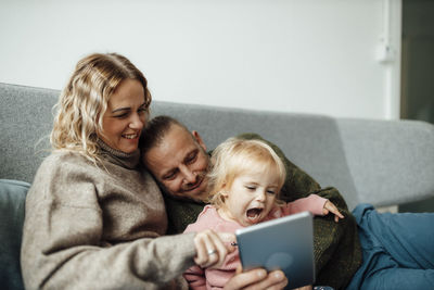 Happy family using tablet pc on sofa at home