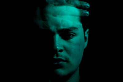 Close-up portrait of young man against black background