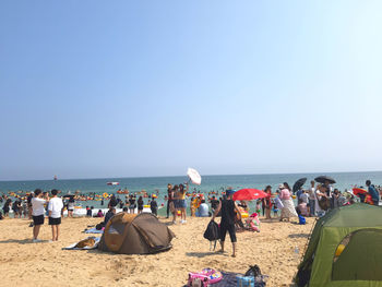 Group of people on beach against clear sky