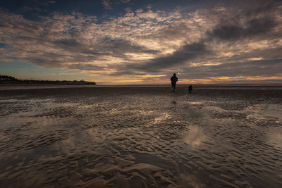 Man standing on beach against sky during sunset