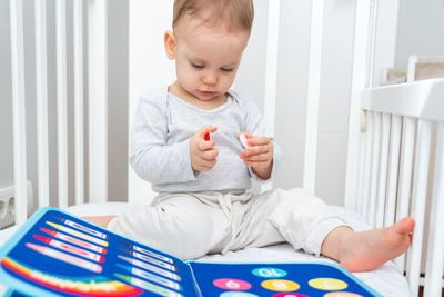 Portrait of cute baby girl sitting on bed at home