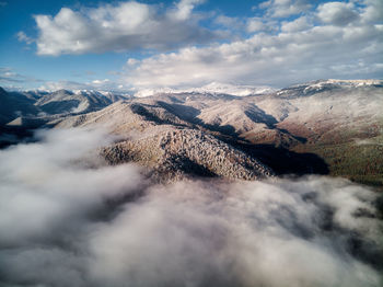 Aerial view, sea of fog and clouds illuminated by the rising sun, snow on the tops of the mountains