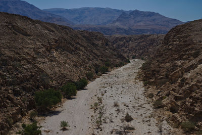 Dirt road amidst mountains against sky