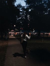 Rear view of woman walking on illuminated street at night