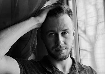 Close-up portrait of handsome mid adult man by window at home