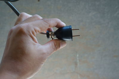 Cropped hand holding electric plug