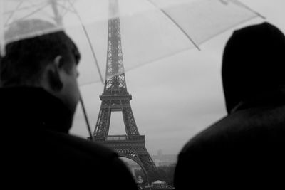 Rear view of men standing against eiffel tower during rain