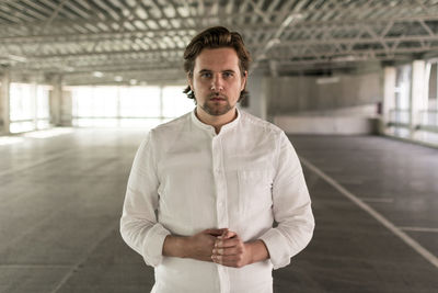 Portrait of young man standing against wall