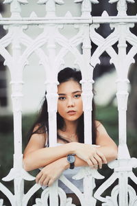 Young woman standing behind white metal fence