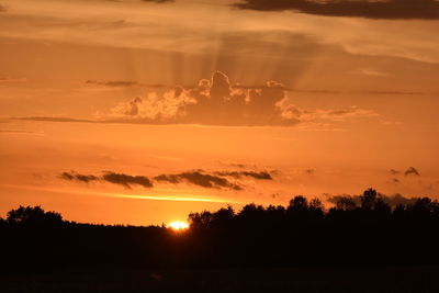 Silhouette trees on field against romantic sky at sunset