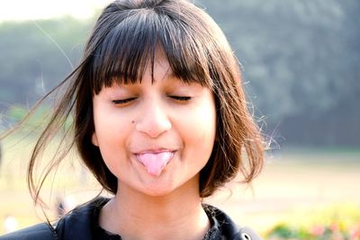 Close-up of smiling woman sticking out tongue outdoors