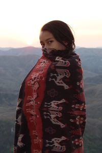 Portrait of young woman standing against sky during sunset