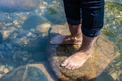 Young girl foot on rock in clear transparent river water from top angle