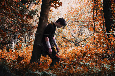 Full length of man with autumn leaves in forest