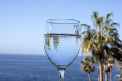 Close-up of beer glass against water