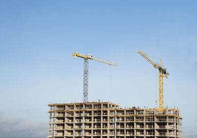 Low angle view of crane against clear blue sky