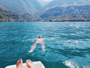 Low section of woman by man swimming in sea