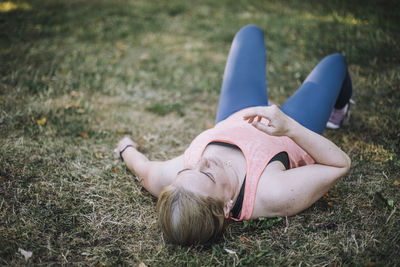 Tired woman lying down on grass at park