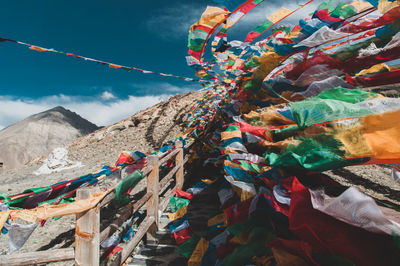 Multi colored flags hanging on mountain against sky