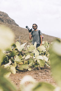 Portrait of young man standing on land against sky