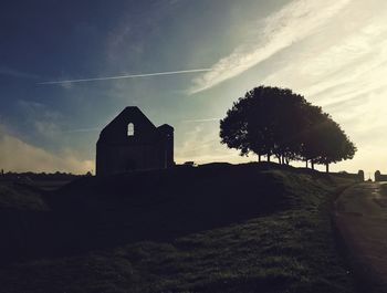 Trees on landscape against cloudy sky