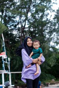 Full length of a smiling happy woman and her son outdoors