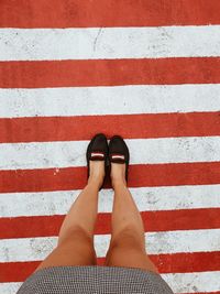 Low section of woman standing on zebra crossing