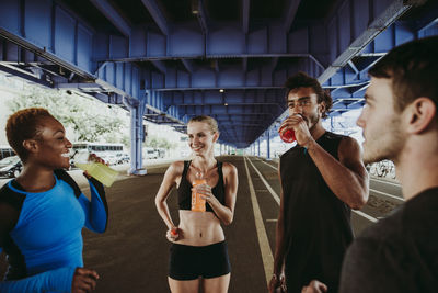 Friends drinking juices while standing on road in city