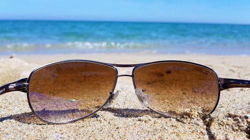 Close-up of sunglasses on sand at beach